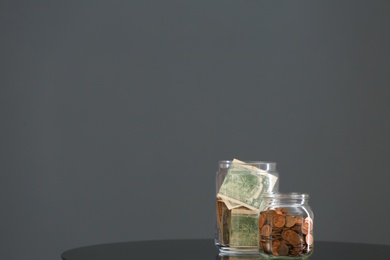 Photo of Donation jars with money on table against grey background. Space for text