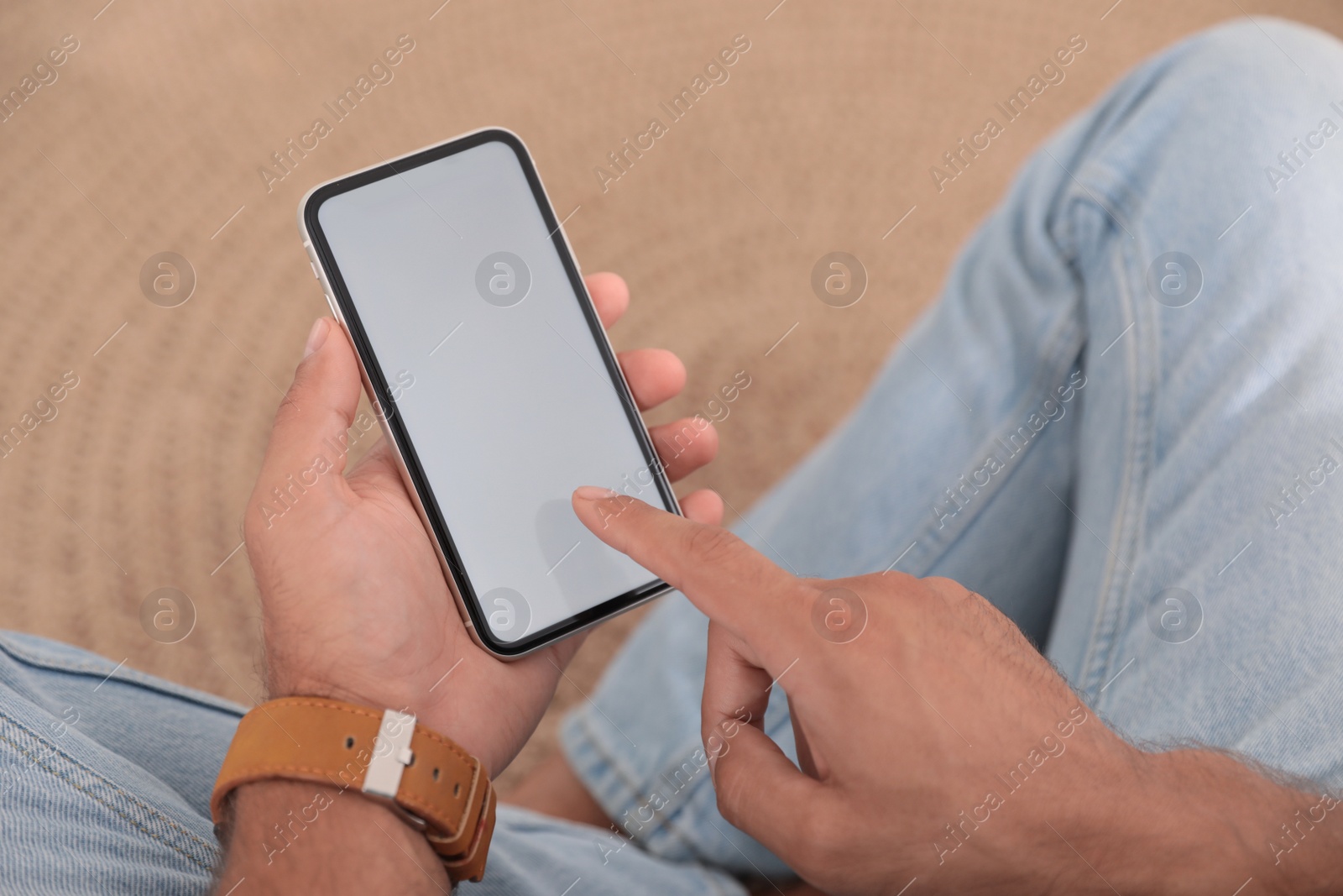 Photo of Man using mobile phone with empty screen indoors, closeup