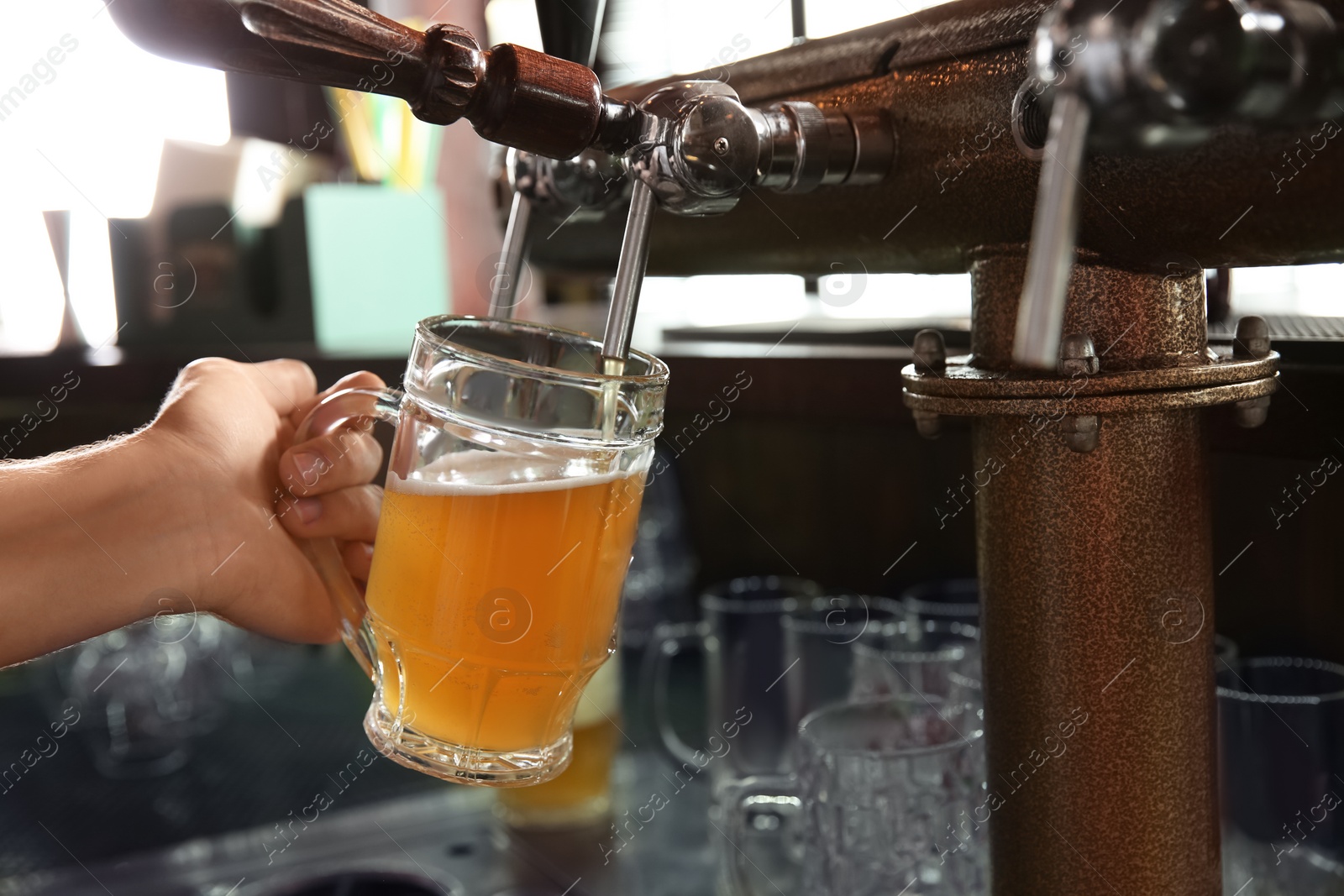 Photo of Bartender pouring beer from tap into glass in bar, closeup