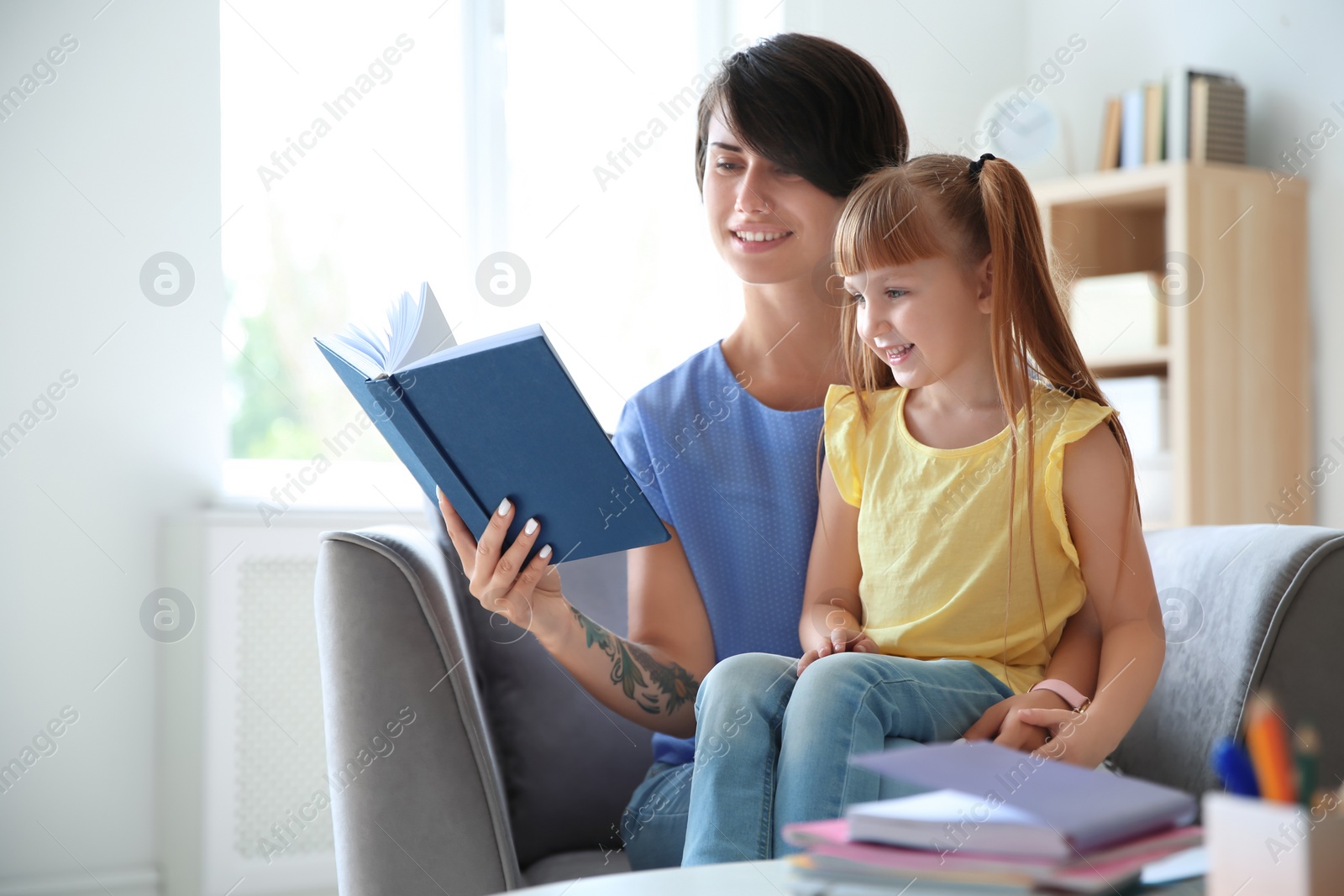 Photo of Young woman helping her child with homework at home. Elementary school