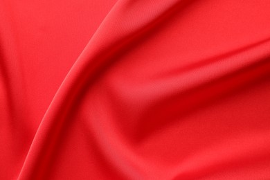 Crumpled red silk fabric as background, top view