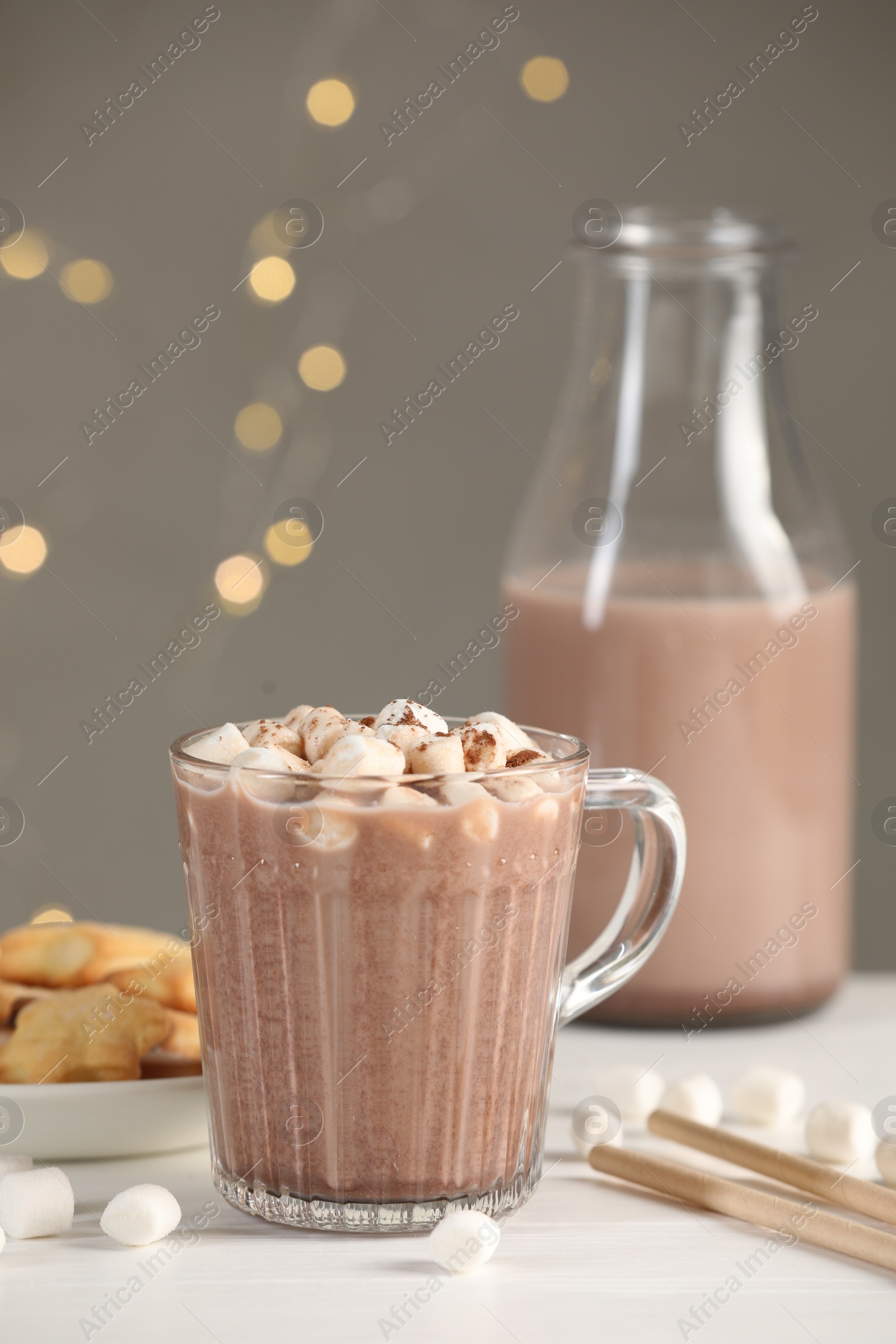 Photo of Cup of aromatic hot chocolate with marshmallows and cocoa powder on white table, closeup