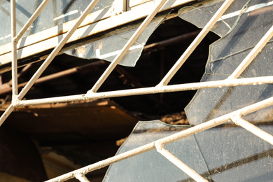 Broken window with metal grid outdoors. Requiring repair