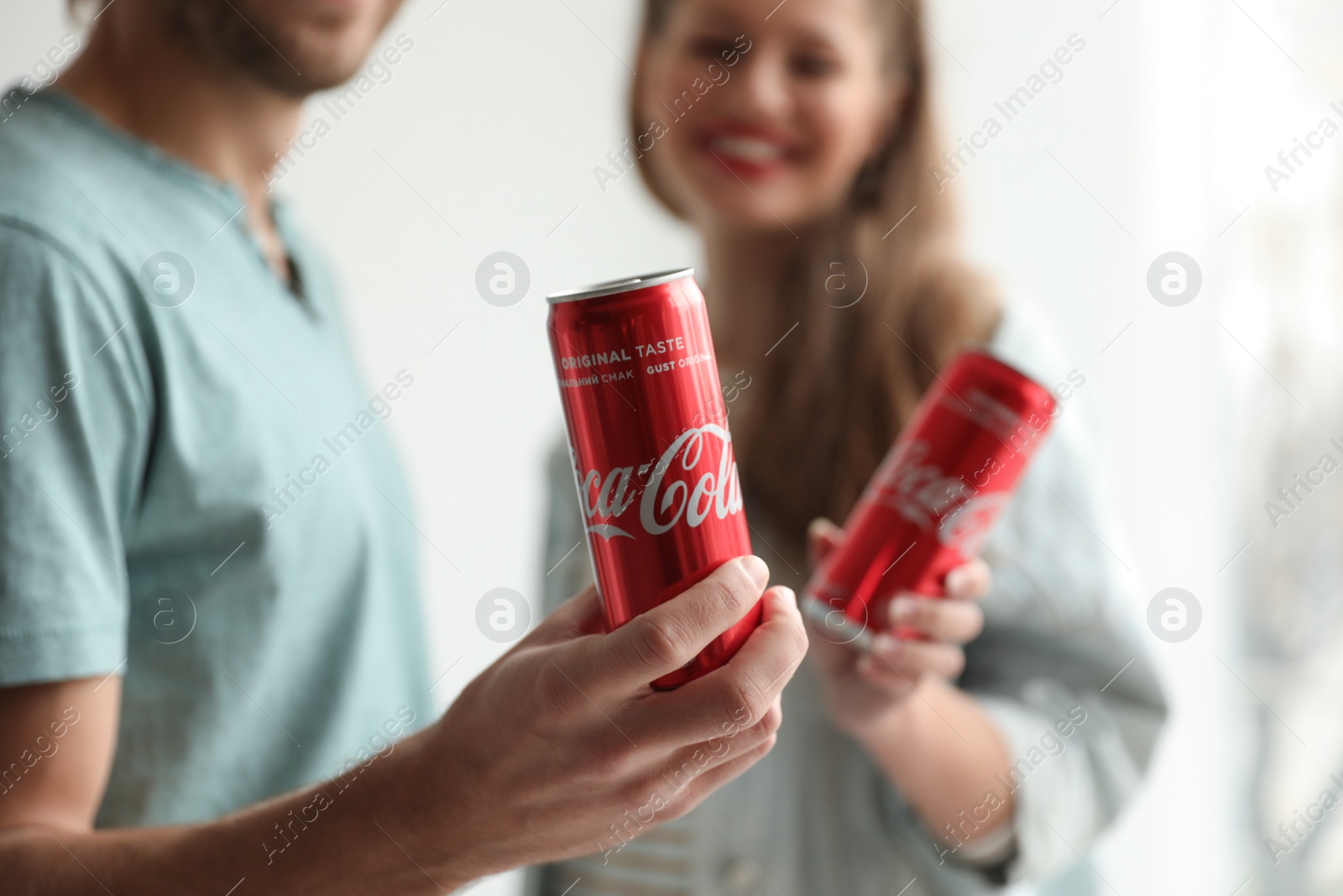 Photo of MYKOLAIV, UKRAINE - NOVEMBER 28, 2018: Young couple with Coca-Cola cans indoors