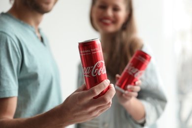 Photo of MYKOLAIV, UKRAINE - NOVEMBER 28, 2018: Young couple with Coca-Cola cans indoors
