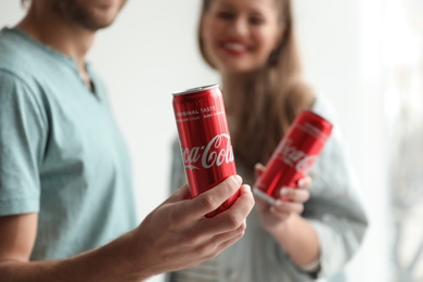 MYKOLAIV, UKRAINE - NOVEMBER 28, 2018: Young couple with Coca-Cola cans indoors