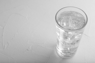 Glass of soda water on white table. Space for text