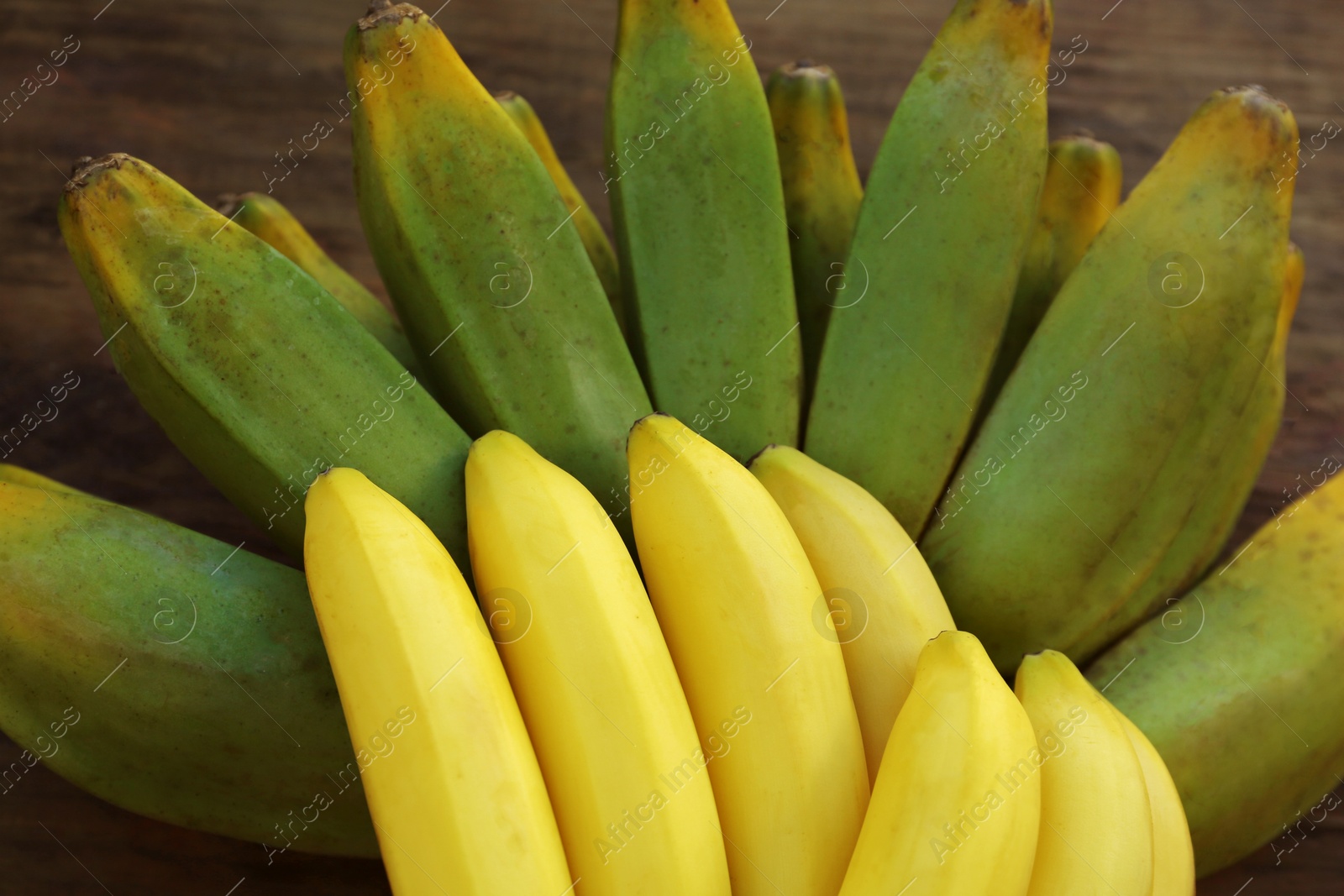 Photo of Bunches of tasty bananas on wooden table, closeup