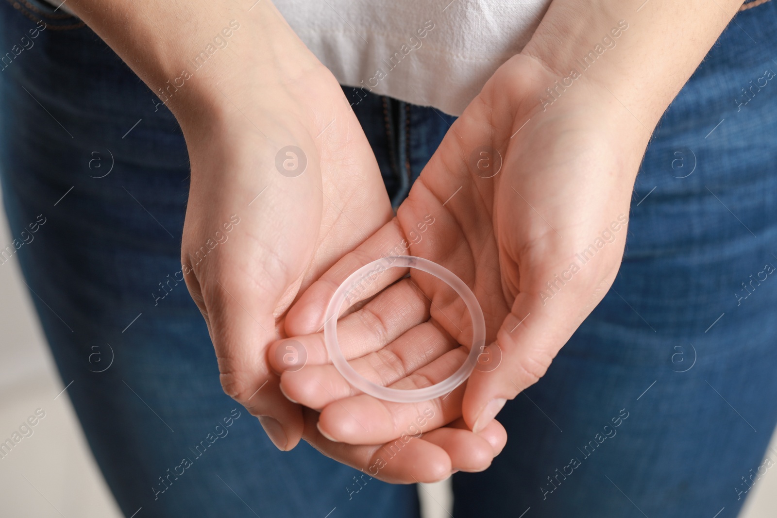 Photo of Woman holding diaphragm vaginal contraceptive ring on blurred background, closeup