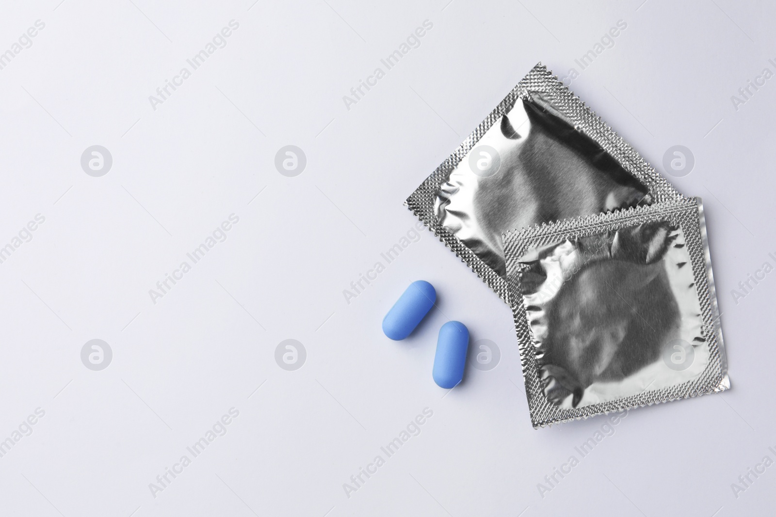 Photo of Pills and condoms on white background, flat lay with space for text. Potency problem