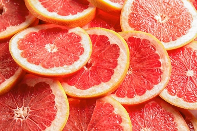 Photo of Many sliced fresh ripe grapefruits as background, closeup