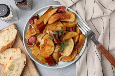 Photo of Delicious baked potato with thin dry smoked sausages served on gray table, flat lay