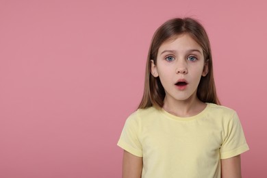 Photo of Portrait of surprised girl on pink background. Space for text