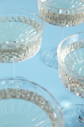 Photo of Glasses of expensive white wine on light blue background, closeup