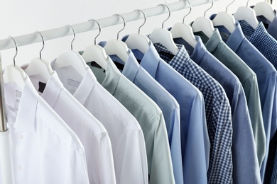 Men's clothes hanging on wardrobe rack against white background