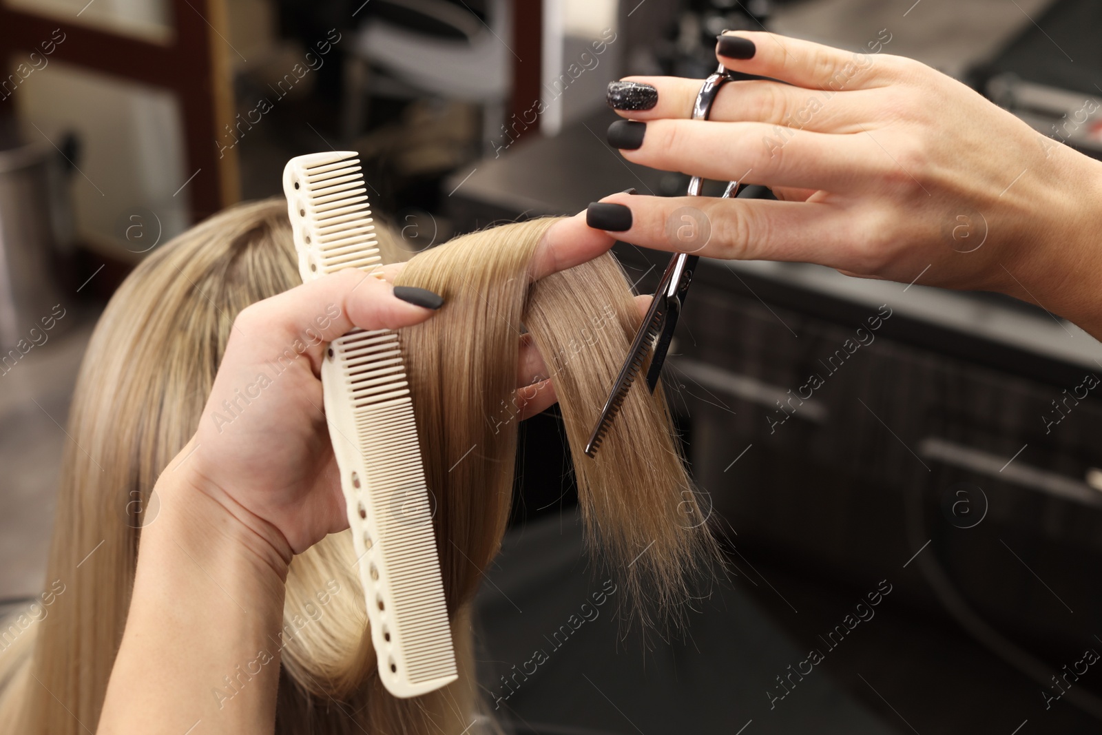 Photo of Professional hairdresser cutting woman's hair in salon, closeup