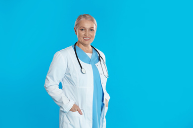 Photo of Portrait of mature doctor with stethoscope on blue background. Space for text