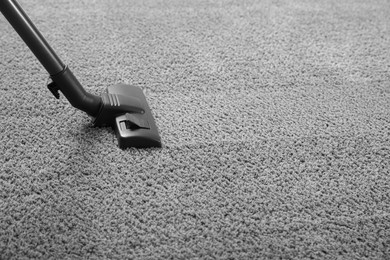 Photo of Removing dirt from grey carpet with modern vacuum cleaner. Space for text