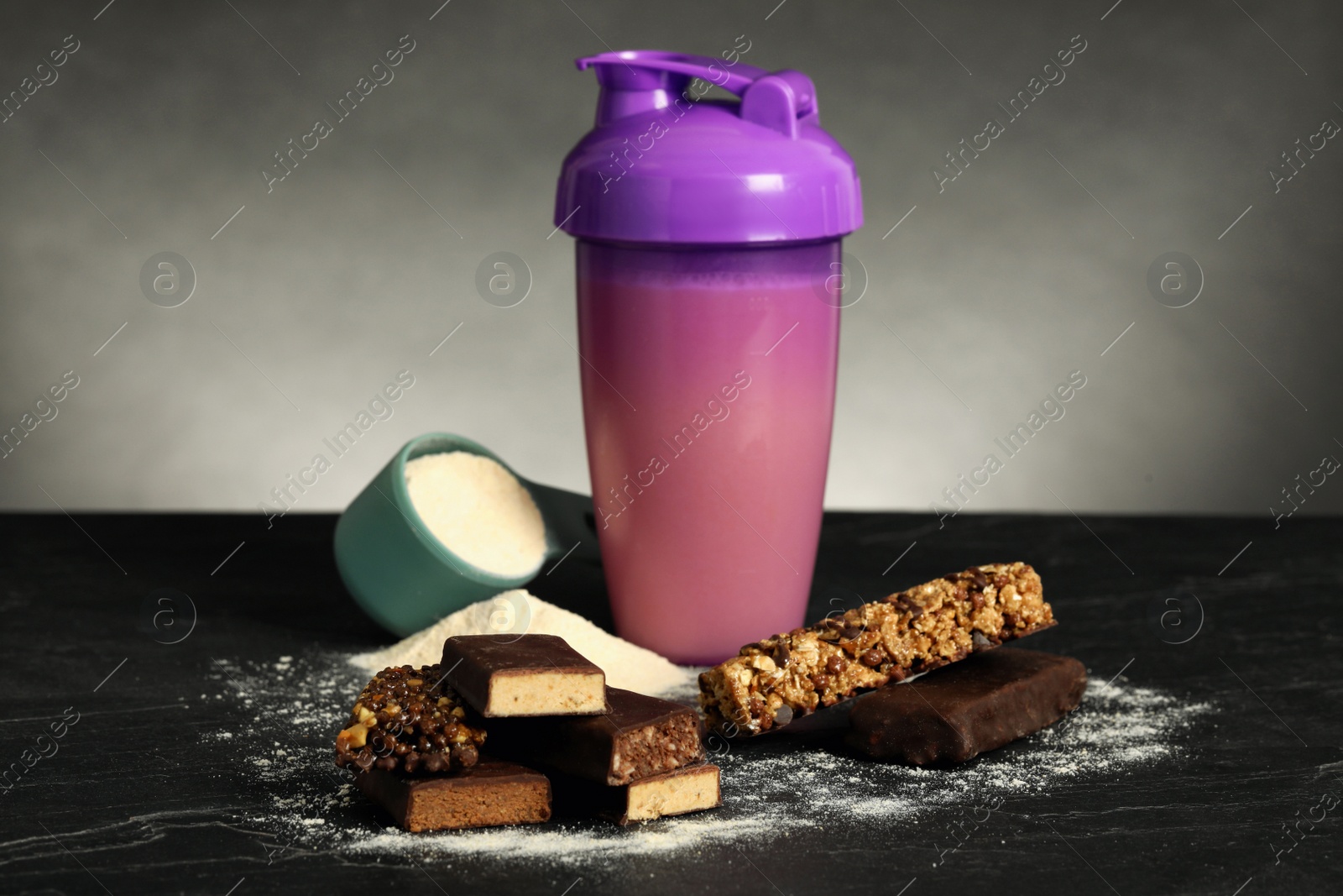 Photo of Different energy bars, protein cocktail and powder on black table
