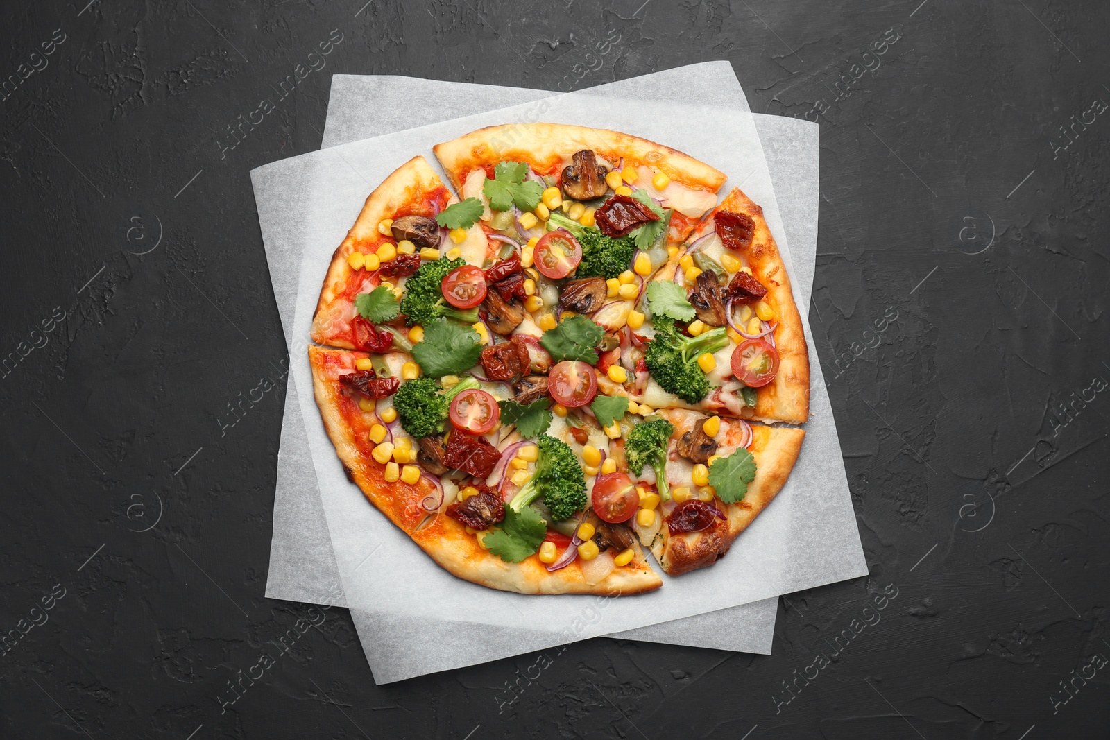 Photo of Delicious vegetarian pizza with mushrooms, vegetables and parsley on black table, top view