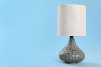 Photo of Stylish new night lamp on light blue background. Space for text