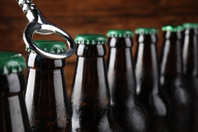 Photo of Opening bottle of beer on wooden background, closeup. Space for text