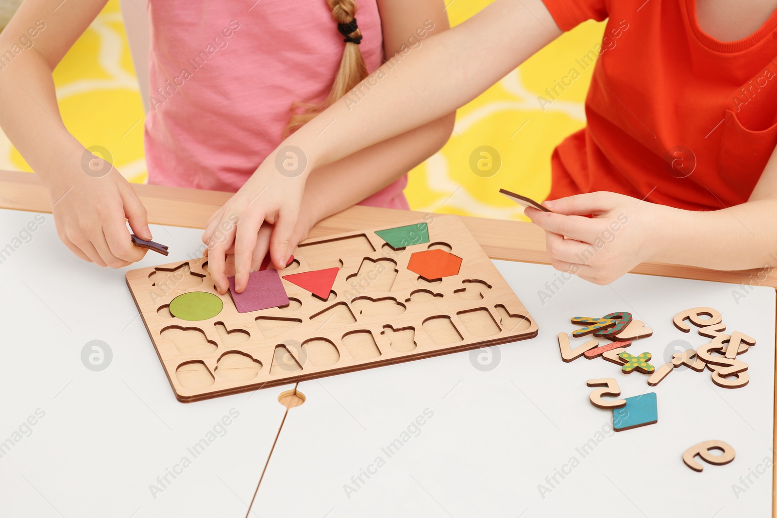 Photo of Children playing with math game kit at desk indoors, closeup. Learning mathematics with fun