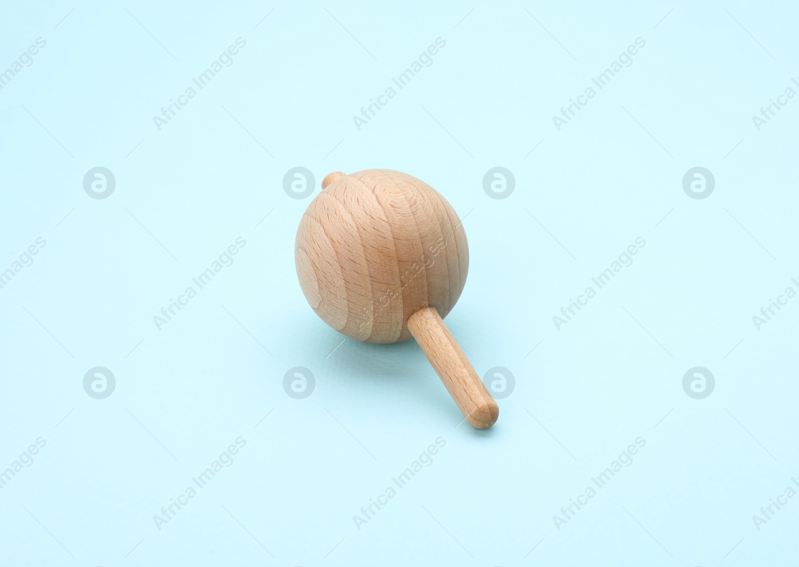 Photo of One wooden spinning top on light blue background. Toy whirligig