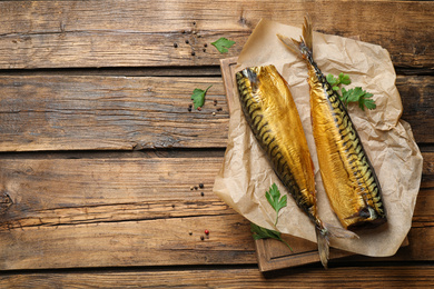 Photo of Tasty smoked fish on wooden table, flat lay. Space for text