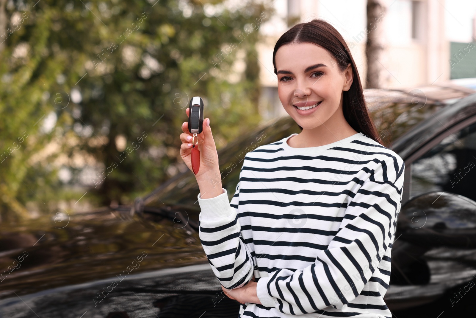 Photo of Woman holding car flip key near her vehicle outdoors