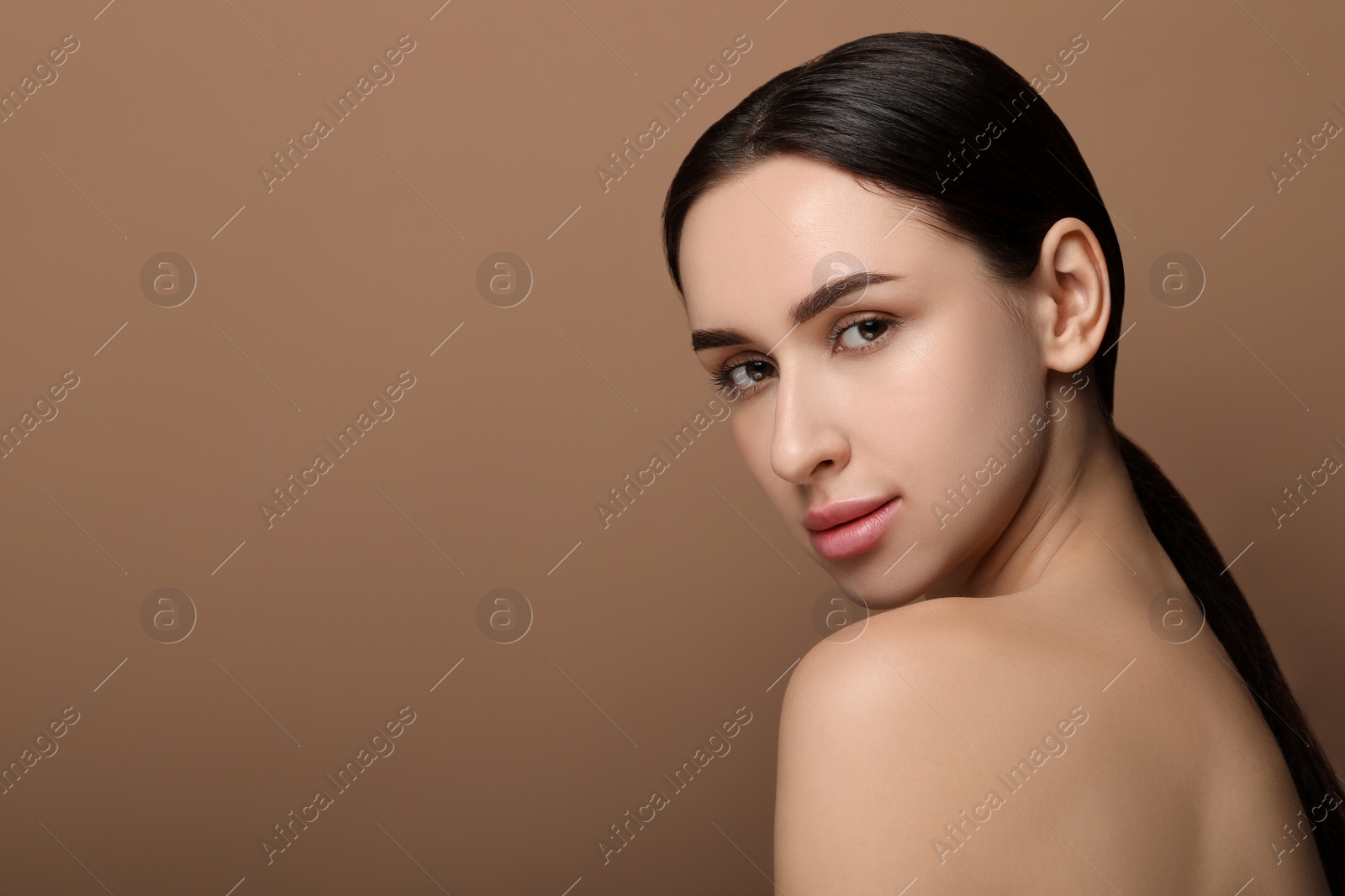 Photo of Portrait of beautiful young woman on brown background. Space for text