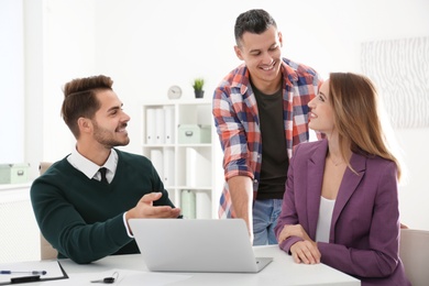 Photo of Real estate agent consulting young couple in office