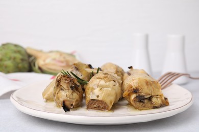 Photo of Delicious pickled artichokes with rosemary served on white table, closeup