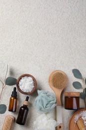 Flat lay composition with different spa products and eucalyptus branches on light grey textured table. Space for text