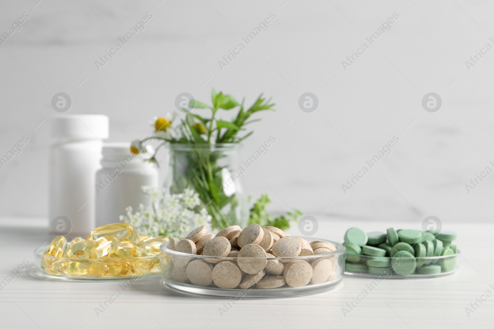 Photo of Different pills on white wooden table, space for text. Dietary supplements