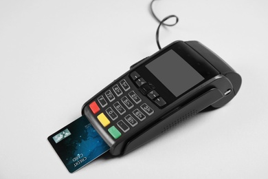 Modern payment terminal with credit card on grey background