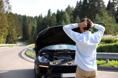 Man near broken car outdoors, back view and space for text