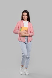 Photo of Teenage girl with textbooks on light grey background