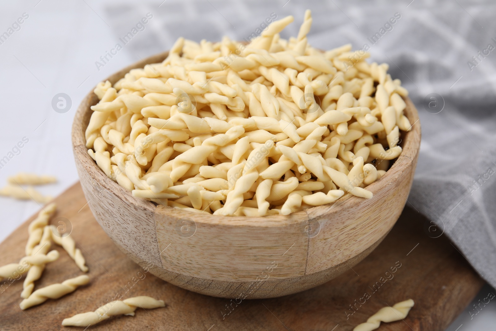 Photo of Bowl with uncooked Italian trofie pasta on table, closeup