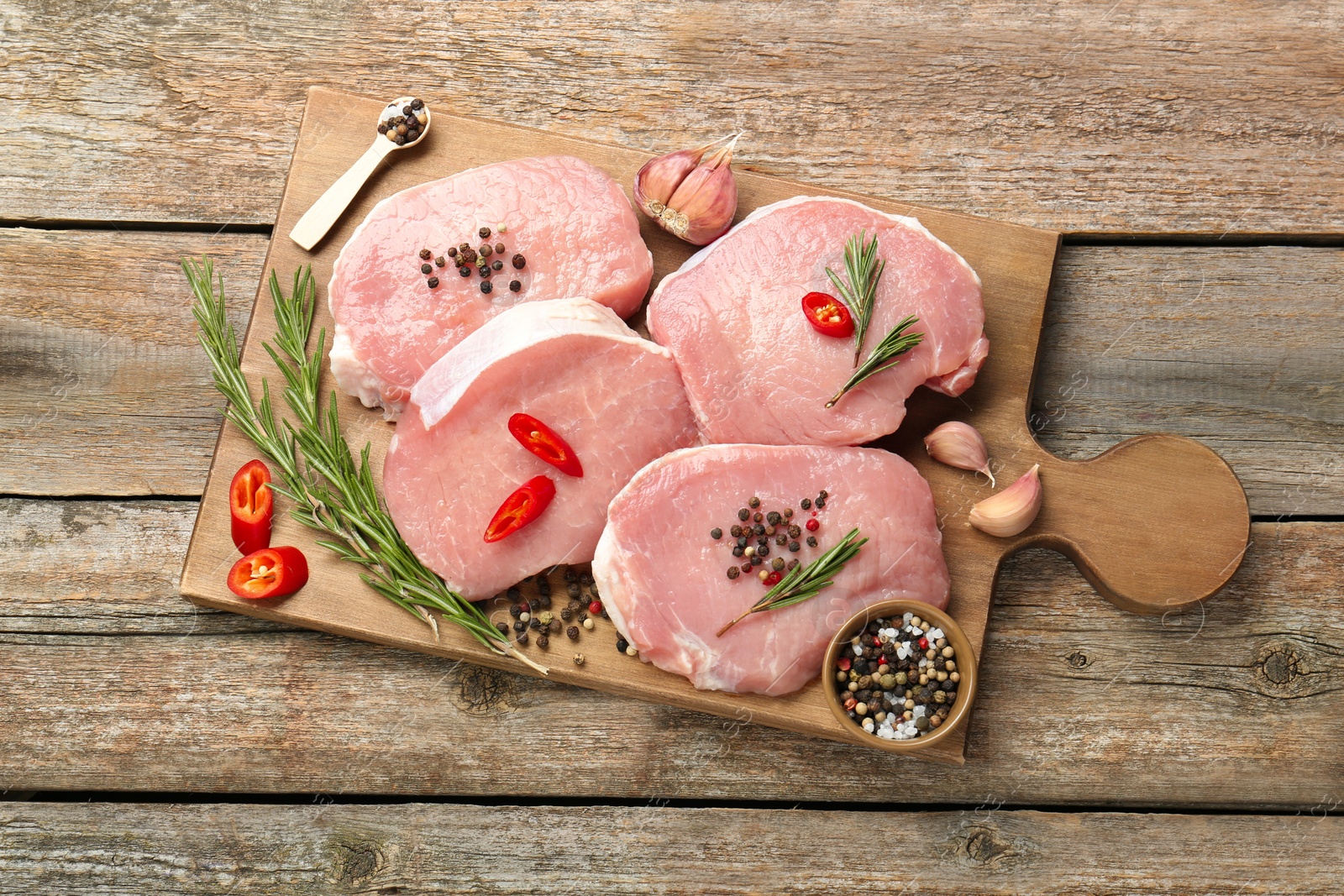 Photo of Pieces of raw pork meat and spices on wooden table, top view