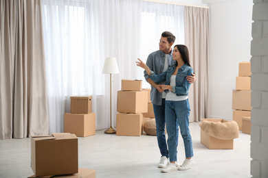 Happy couple in room with cardboard boxes on moving day