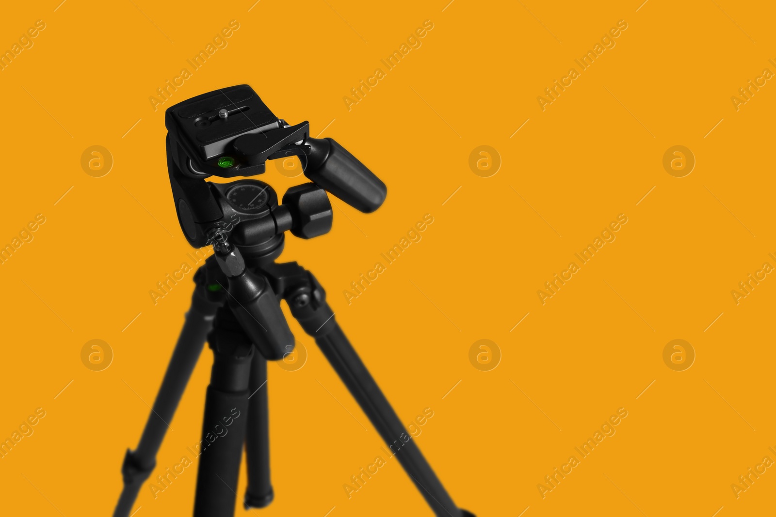 Photo of Modern tripod on yellow background. Space for text