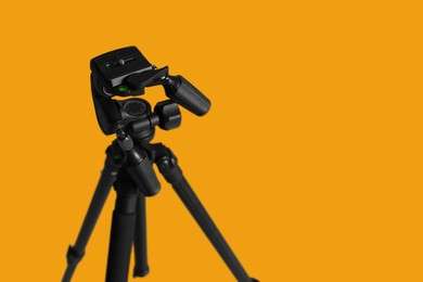 Modern tripod on yellow background. Space for text