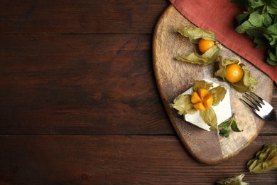 Delicious dessert decorated with physalis fruit on wooden table, flat lay. Space for text