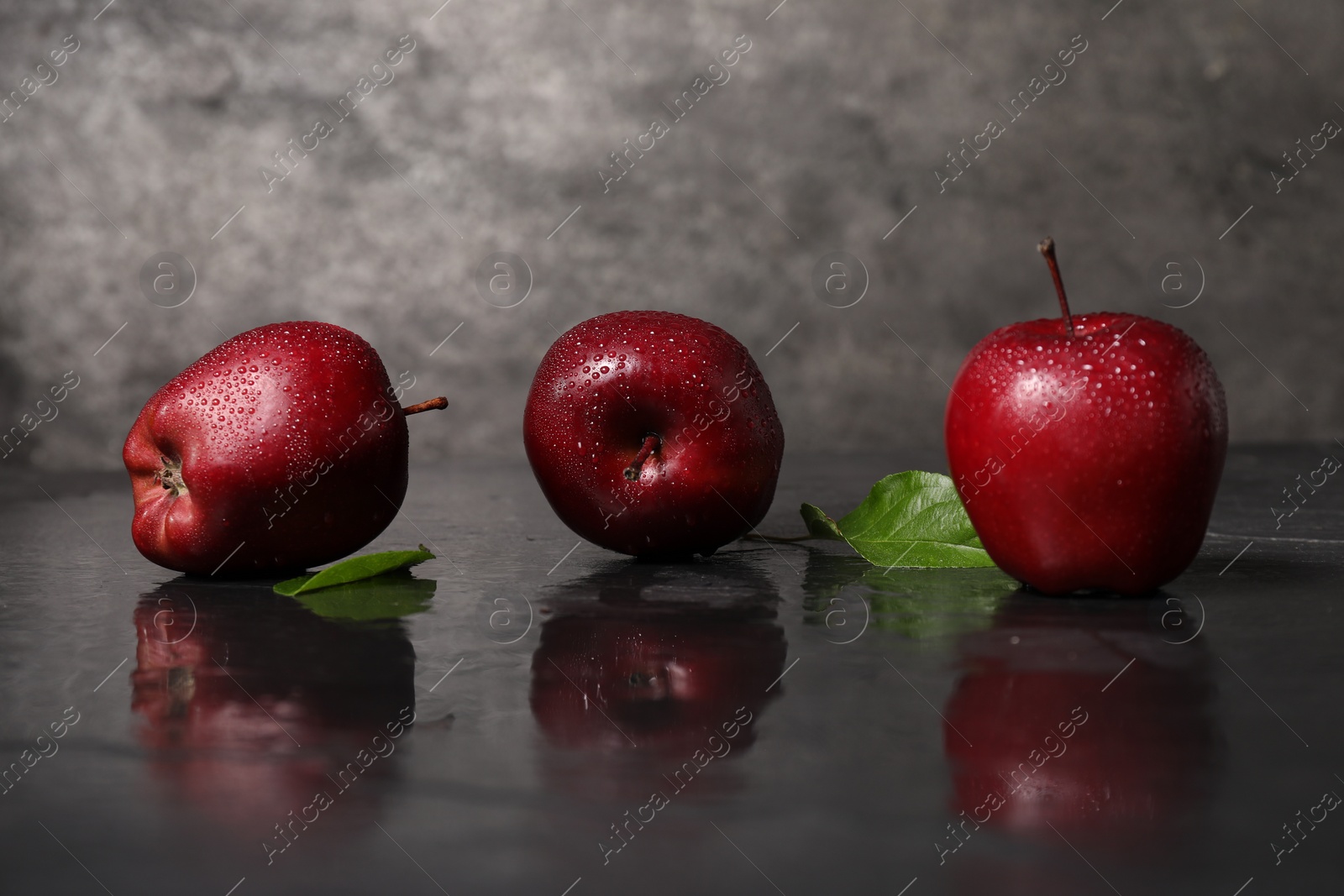 Photo of Wet red apples on dark grey table