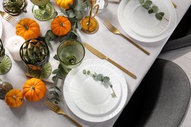 Beautiful autumn table setting. Plates, cutlery, glasses, pumpkins and floral decor, flat lay