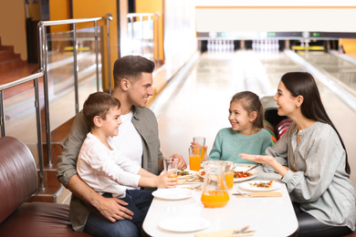 Photo of Happy family with pizza and drinks in bowling club