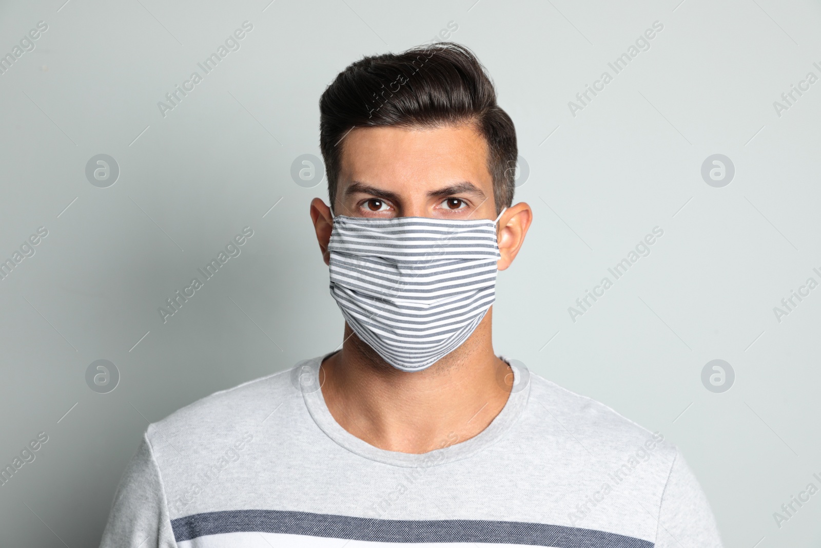 Photo of Man in protective face mask on light grey background