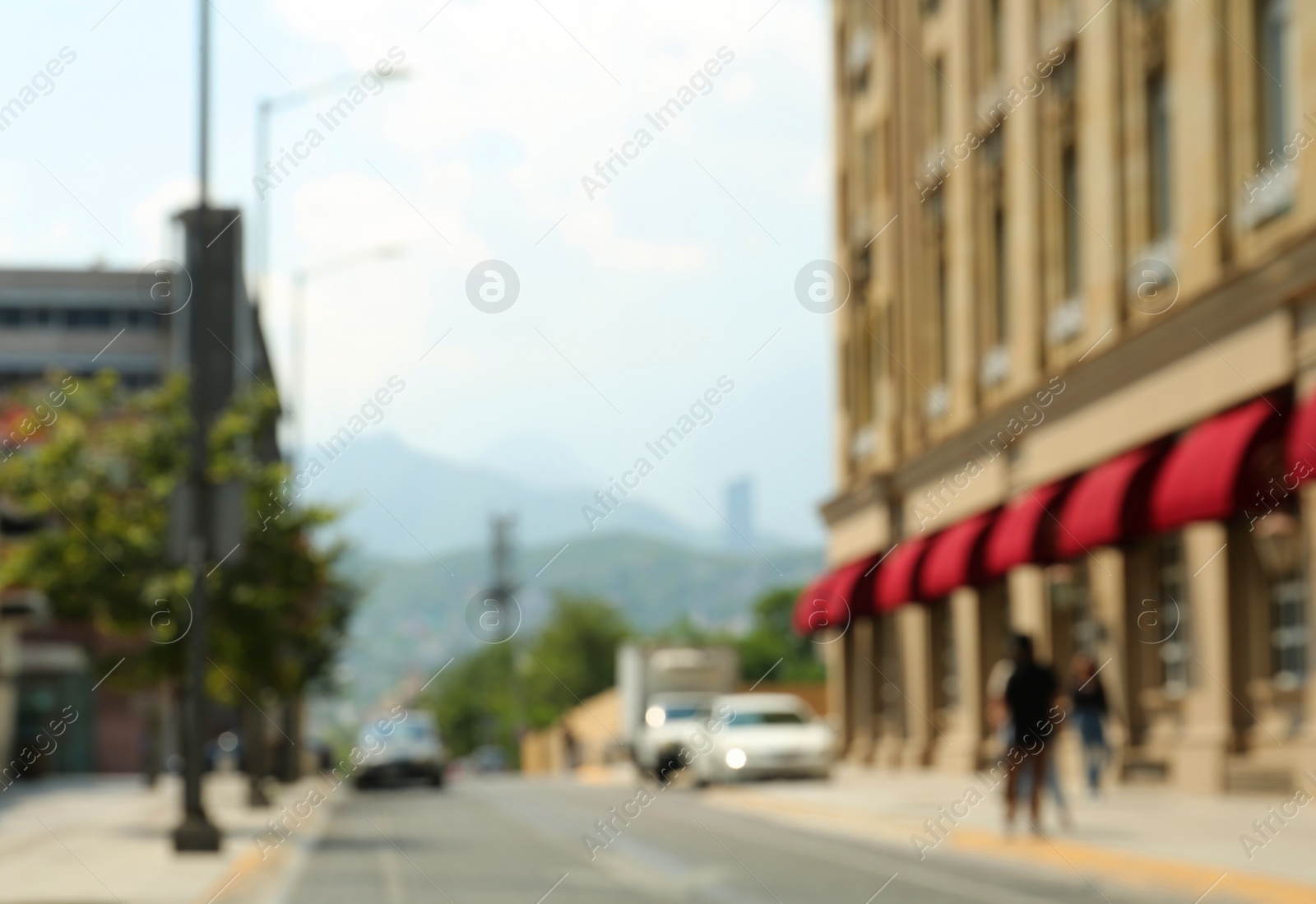 Photo of Blurred view of city street with buildings and parked cars