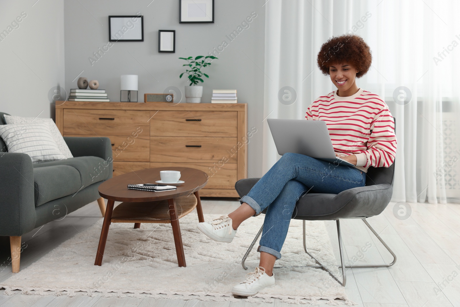 Photo of Beautiful young woman using laptop in room, space for text